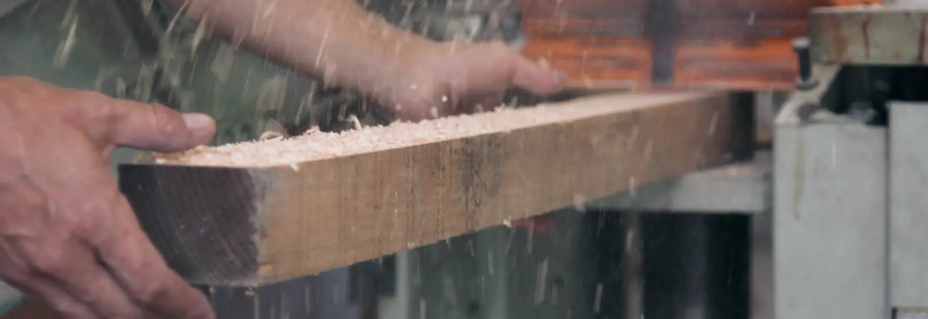 Homme qui rabote un épaisse planche de bois