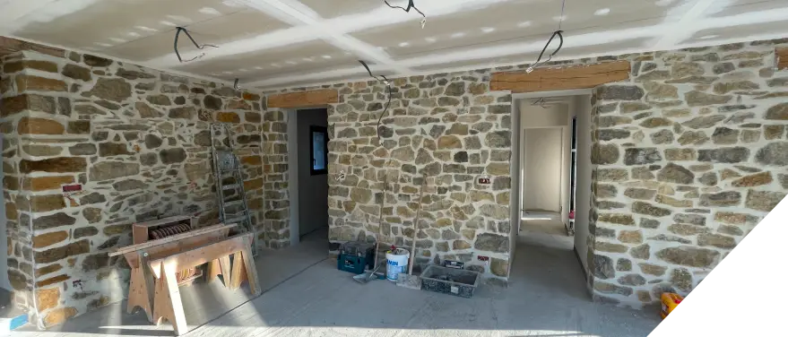 Pièce en travaux avec murs en pierre anciennes